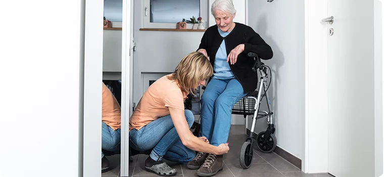 Eine Frau hilft einer älteren Frau beim Schuhe anziehen