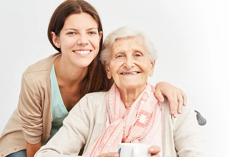 Eine jüngere und eine ältere Frau lachen in die Kamera