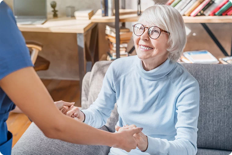 Ältere Frau sitzt lachend auf dem Sofa