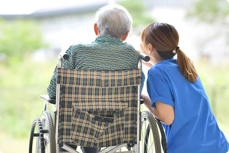 Pflegerin zeigt Mann im Rollstuhl etwas