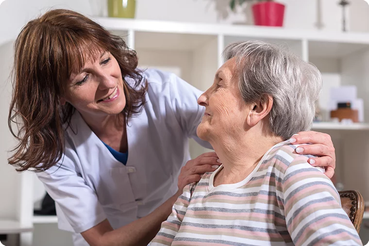 Frau im Rollstuhl und Pflegerin lachen zusammen