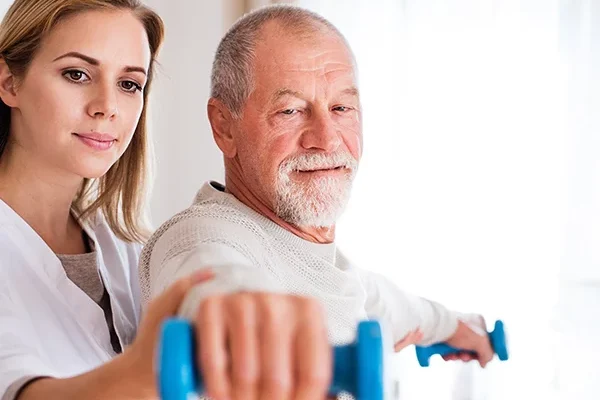 Pflegerin hilft Mann beim Hanteltraining